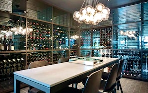 A wine cellar with glass walls and shelves of wine bottles. - CASA DELUXE #5 - Pool Gym Sauna Spa City Views Parking (South Yarra)