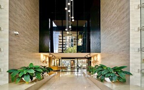 Eine moderne Lobby mit hoher Decke, großen Fenstern und symmetrisch angeordneten Pflanzen.
