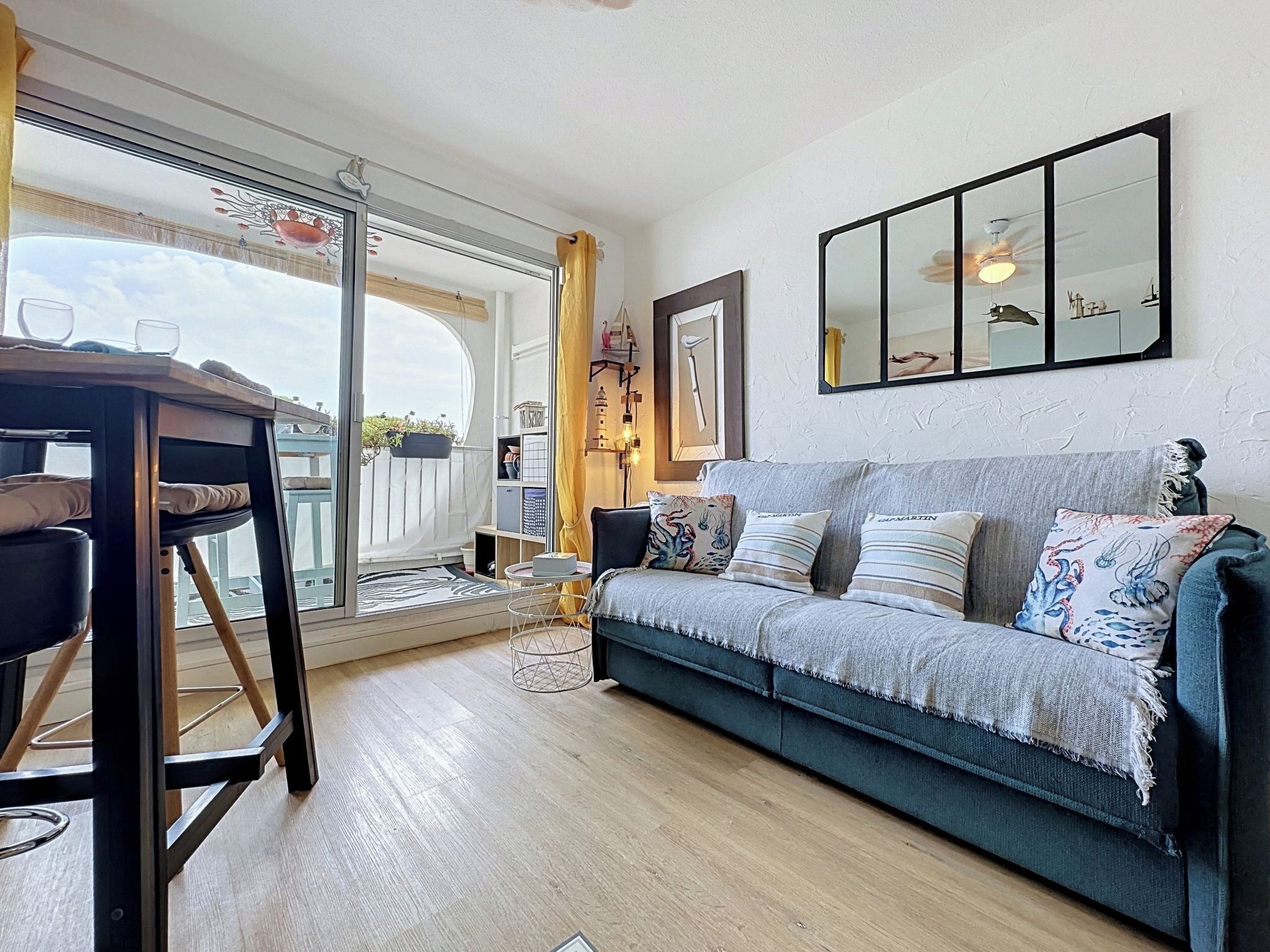 A living room with a sofa, a coffee table, a chair, a large window, and a ceiling fan.