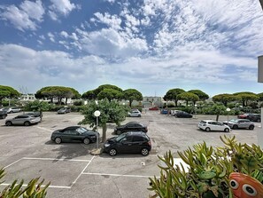 Ein Parkplatz mit mehreren Autos, Bäumen und blauem Himmel.