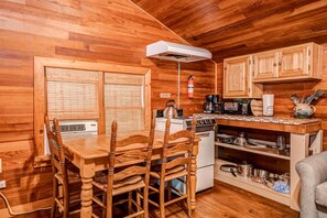 Un interior de madera con una mesa de comedor, sillas, una estufa y armarios de cocina.