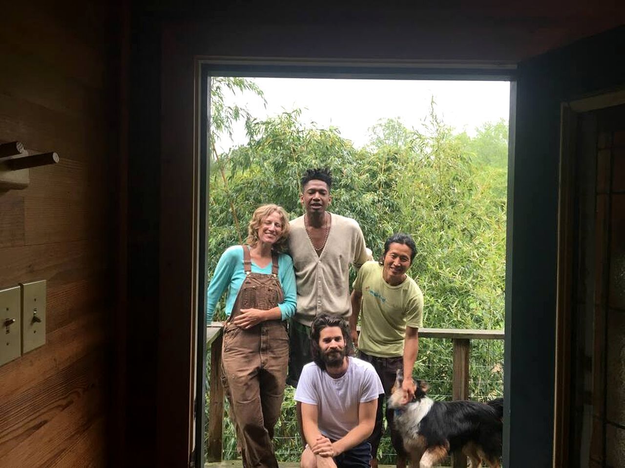A group of people standing on a balcony with a wooden railing, overlooking a lush green landscape.