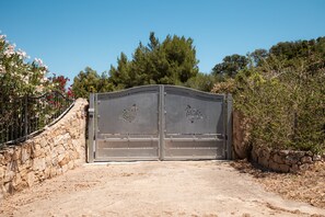 Ein begrenzter Zugang mit einer Steinmauer an der Seite und einem schmiedeeisernen Tor mit Verzierungen.
