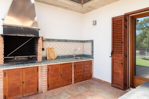 Een keuken met een ingebouwde grill, een spoelbak en houten kastjes.