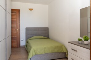 Een slaapkamer met een bed, een kaptafel, een spiegel en een deur.