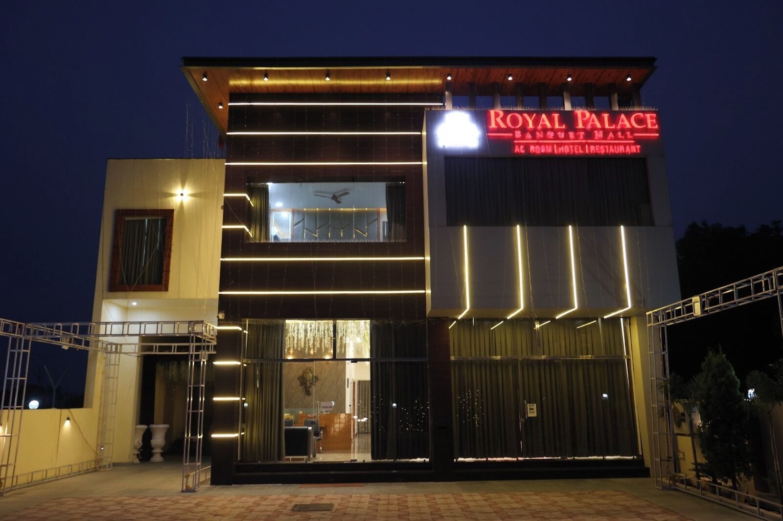 A hotel with a modern facade, a prominent sign reading 'Royal Palace Banquet Hall,' and a visible entrance with a glass door.