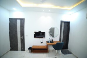 A hotel room with a desk, chair, TV, mirror, and two doors. - HOTEL ROYAL PALACE (Bhiwani)