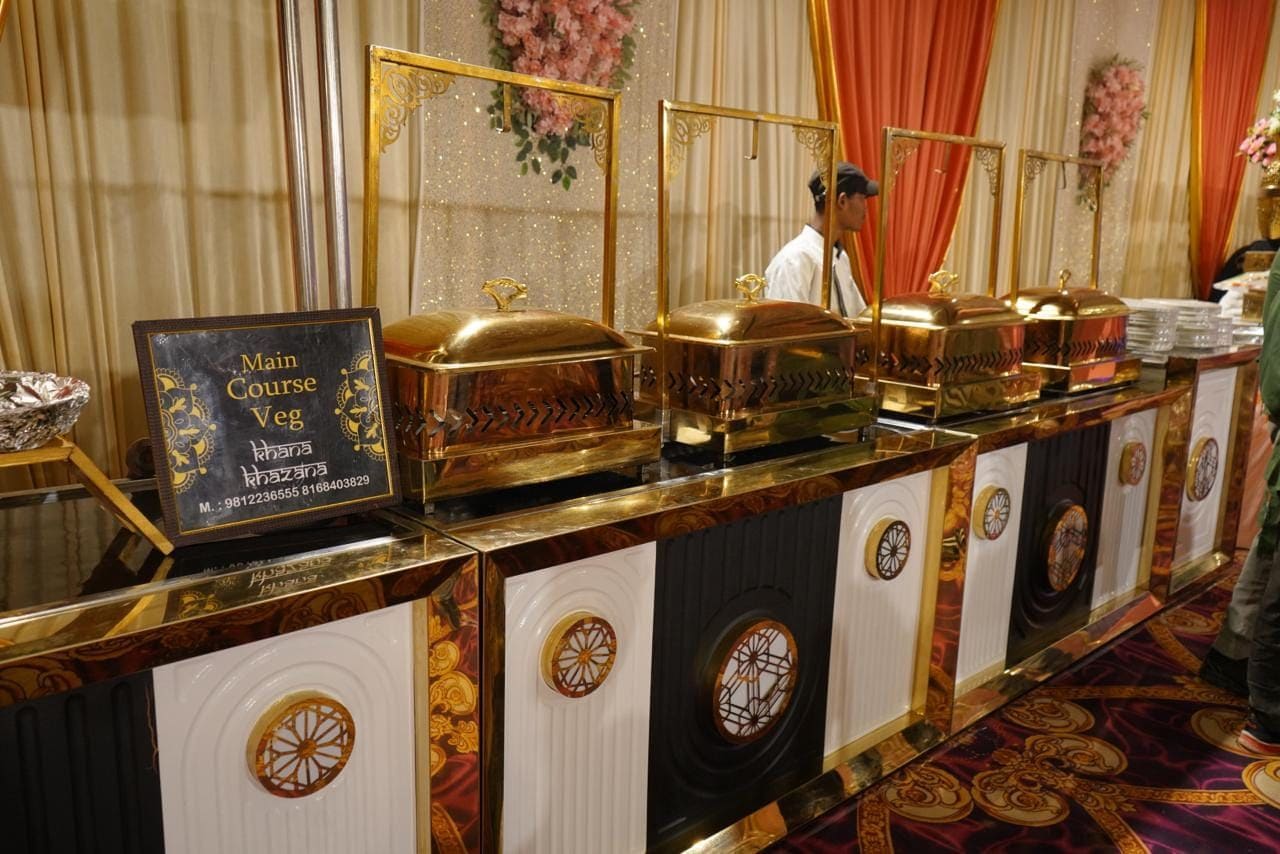 Ein Buffet mit mehreren vergoldeten Serviergeschirr und einem Schild, das den Bereich für Gemüse als Hauptspeise kennzeichnet.