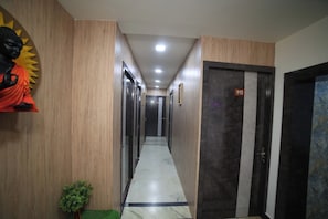 A hotel hallway with wooden paneling, a statue, a plant, and a door marked '110'.