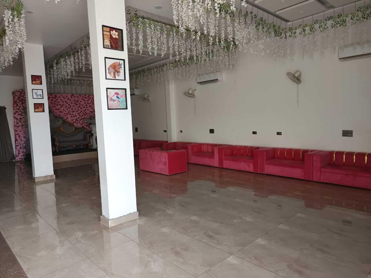Eine großzügige Lobby mit einer langen Reihe roter Sofas, einem Fliesenboden und blumengeschmückten Dekorationen.