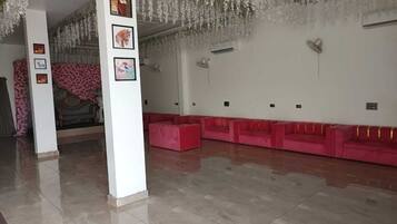 Eine großzügige Lobby mit einer langen Reihe roter Sofas, einem Fliesenboden und blumengeschmückten Dekorationen.