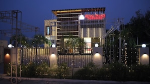 A hotel entrance with a gated driveway, a sign reading 'Royal Palace,' and a modern building facade. - HOTEL ROYAL PALACE (Bhiwani)