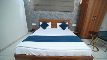 Una habitación de hotel moderna con una cama grande, cabecero de madera, una mesita y un armario.