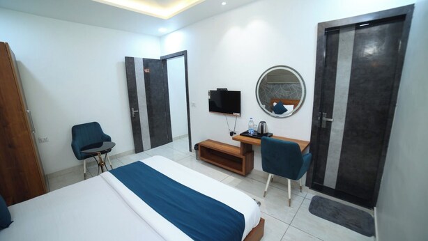 A hotel room with a bed, a desk, a chair, a TV, and a wardrobe. - HOTEL ROYAL PALACE (Bhiwani)