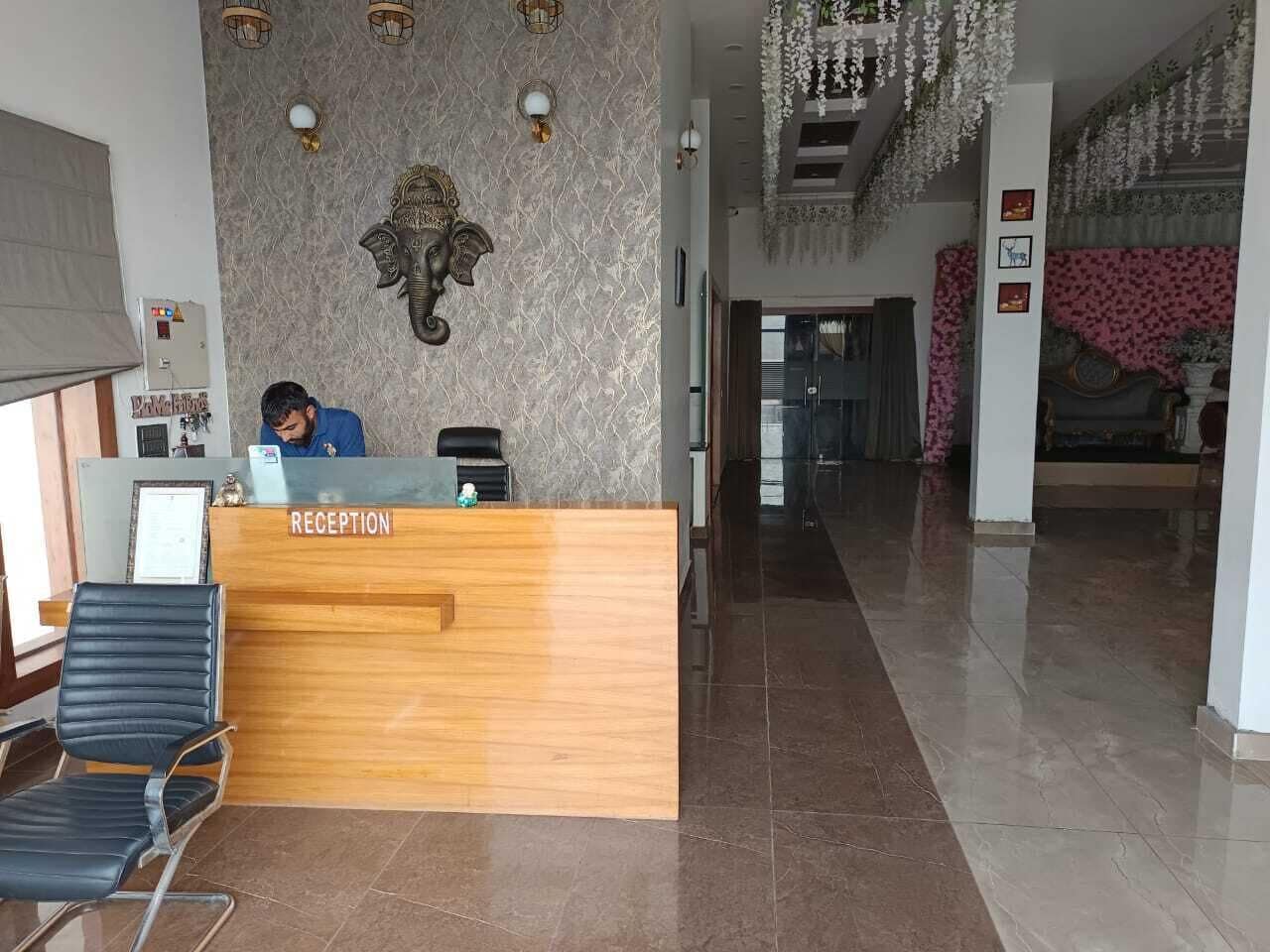 En receptionsdisk med en receptionist, en vägg med ett mönster och en kristallkrona.