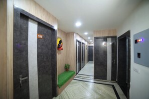 Un pasillo de hotel con puertas numeradas 104 y 110, una pequeña planta verde y una estatua en la pared.