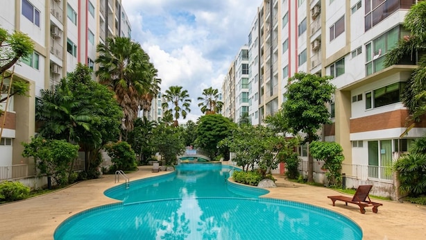A swimming pool surrounded by multi-story residential buildings, with a bridge in the background. - Room-modern Condo Room With Private Faci (Bangkok)