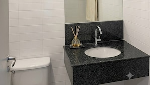 A bathroom with white tiles, a black countertop, a sink, a mirror, and a toilet. - Room-modern Condo Room With Private Faci (Bangkok)