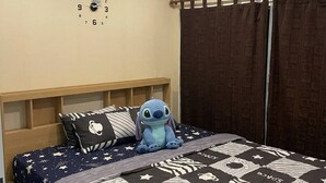 A bedroom with a bed, a wall clock, an air conditioner, and a window with curtains. - Room-modern Condo Room With Private Faci (Bangkok)