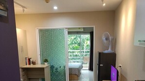 A modern kitchen with a microwave, oven, and a fan. There is a sliding glass door leading to a balcony with a bed and a chair. - Room-modern Condo Room With Private Faci (Bangkok)