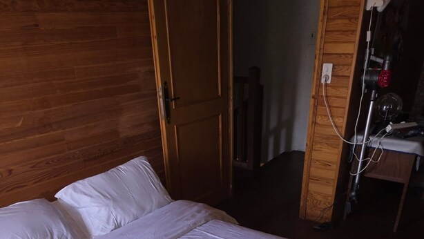 Un lit avec une literie blanche, une tête de lit en bois et une armoire en bois dotée d’un miroir.