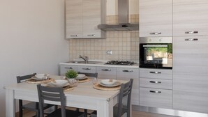 Una cucina moderna con tavolo da pranzo per quattro persone, elettrodomestici in acciaio inossidabile e mobili chiari.