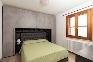 A bedroom with a bed, a nightstand, a dresser, a window, and a radiator. - Villa Certosina by Wonderful Italy (Siniscola)