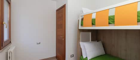 Una habitación con literas, una puerta de madera, un radiador y una ventana.