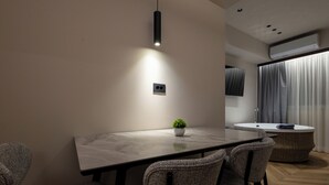 A modern dining area with a rectangular table, four chairs, a small potted plant, and a pendant light. - Lux Suites Athens (Athina)