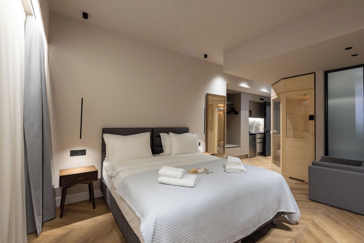 Ein modernes Hotelzimmer mit einem großen Bett, Nachttischen, einem Kleiderschrank und einem begehbaren Kleiderschrank.