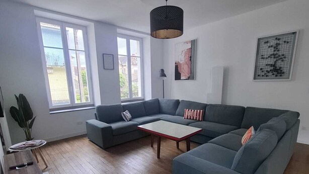 Un saló modern amb un sofà modular, una taula de centre i una zona menjador amb taula i cadires de fusta.