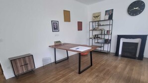 Una habitació amb sòl de fusta, una taula, una estanteria i una llar de foc.