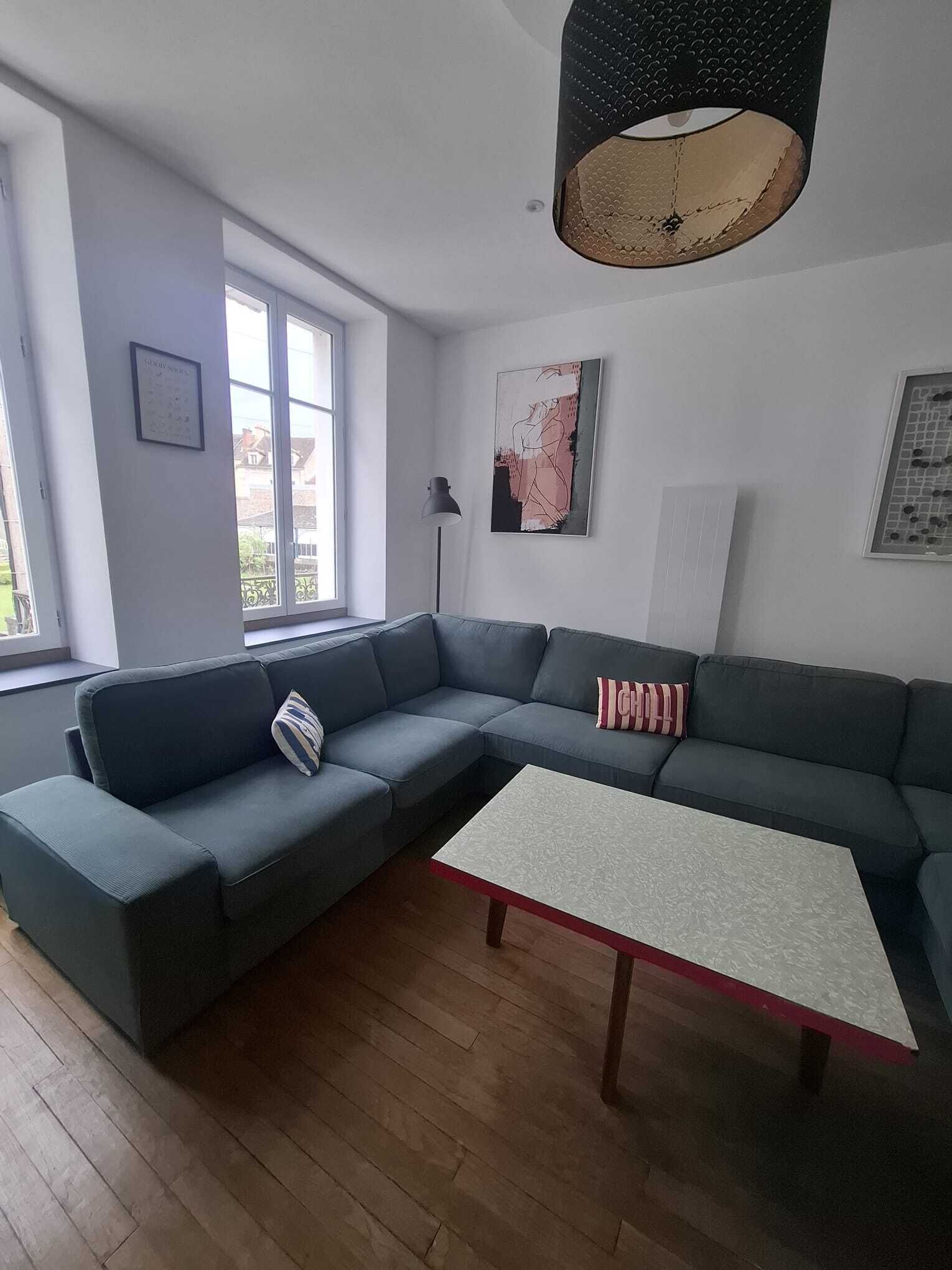 En stue med en modulsofa, et sofabord, en gulvlampe og billedkunst på væggene.