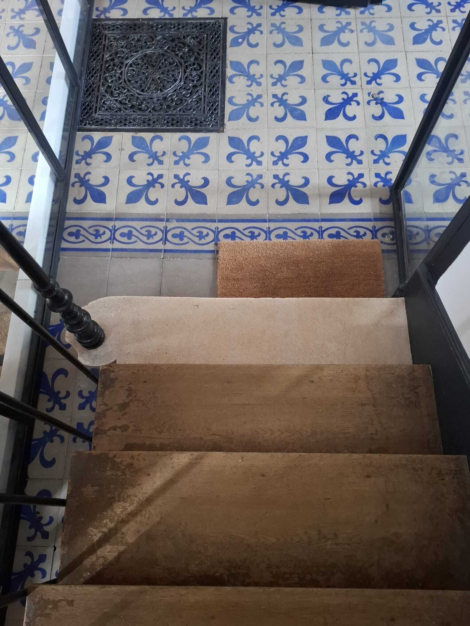 Un escalier avec un mur orné de motifs et une rampe métallique.