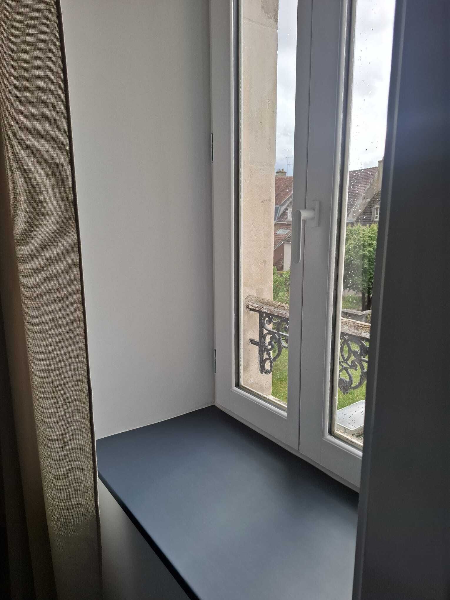 A room with a window overlooking a balcony with a metal railing.