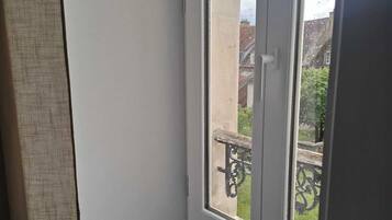 A room with a window overlooking a balcony with a metal railing.