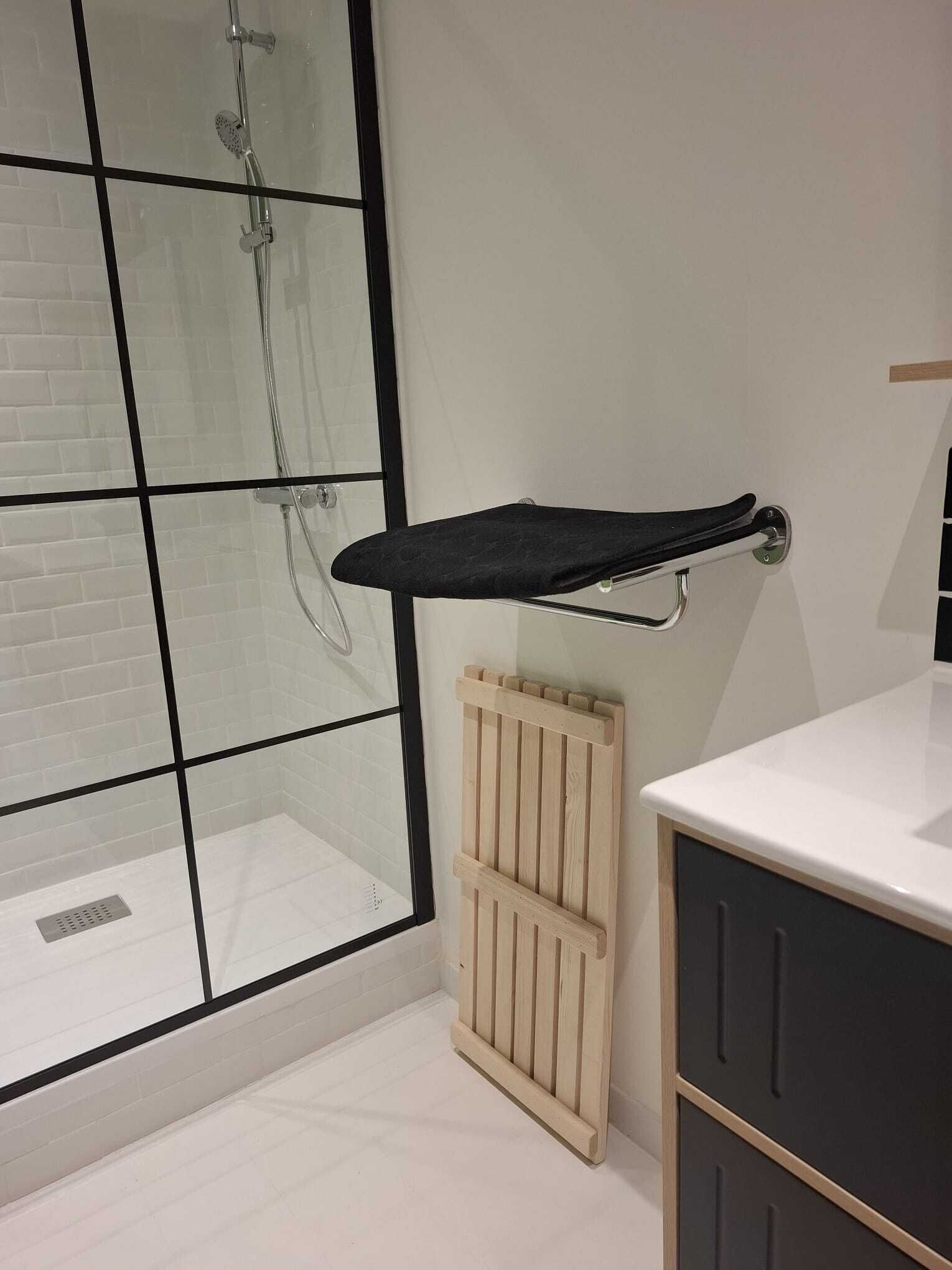 A bathroom with a glass shower enclosure, a towel rack, a radiator, and a dark-colored cabinet.
