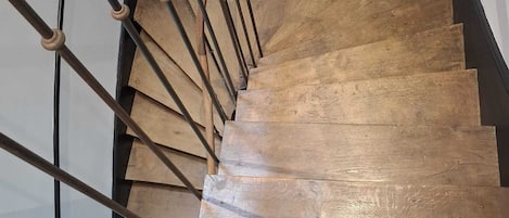 Un escalier en bois avec une rampe métallique et un mur noir.