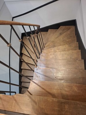 A wooden staircase with a metal handrail and black wall. - 200-square-meter apartment - 5 bedrooms - 3 bathrooms (Avallon)