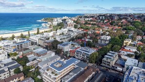 A coastal cityscape with a beach, residential buildings, and a prominent construction crane. - Bright Bondi Beach Studio (Bondi Beach)
