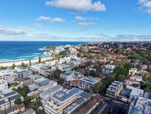 A coastal cityscape with a beach, residential buildings, and a prominent construction crane. - Bright Bondi Beach Studio (Bondi Beach)