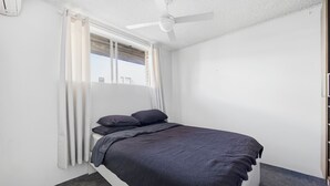A bedroom with a single bed, a ceiling fan, and a window with curtains. - Bright Bondi Beach Studio (Bondi Beach)