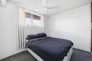 A bedroom with a single bed, a ceiling fan, and a window with curtains. - Bright Bondi Beach Studio (Bondi Beach)