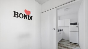 A modern kitchen with white cabinets and a built-in microwave. - Bright Bondi Beach Studio (Bondi Beach)