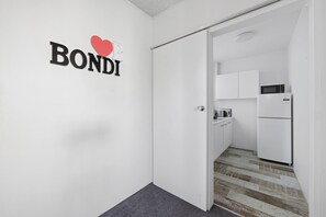 A modern kitchen with white cabinets and a built-in microwave. - Bright Bondi Beach Studio (Bondi Beach)