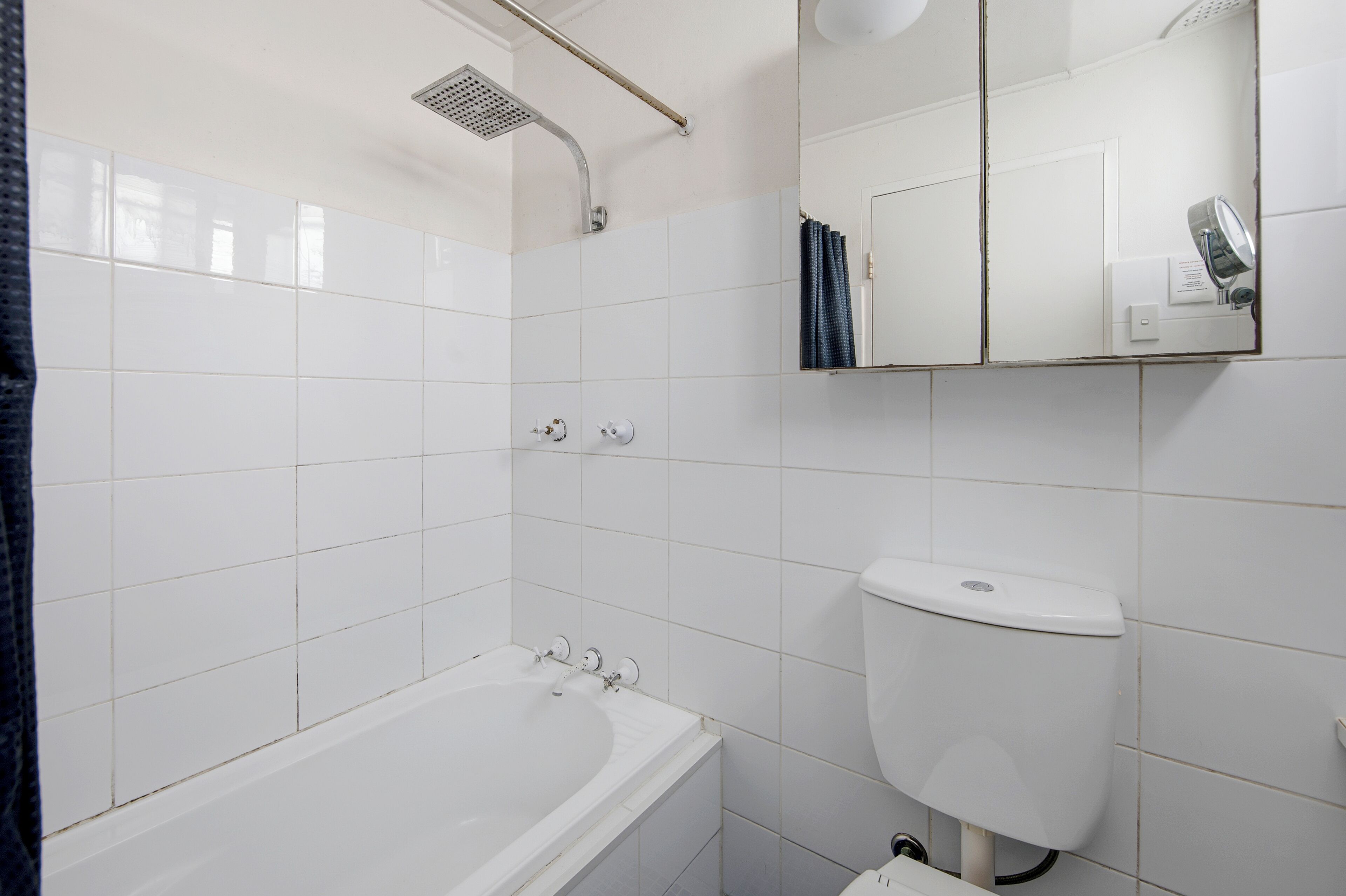 Ein Badezimmer mit einer weißen Badewanne, einer Duschbrause, einer Toilette und einem Spiegel.