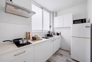 A modern kitchen with white cabinetry, a built-in stove, a microwave, and a refrigerator. - Bright Bondi Studio | 2 Min Walk to Beach, Bath, Full Kitchen, Sleeps 4 (Bondi Beach)