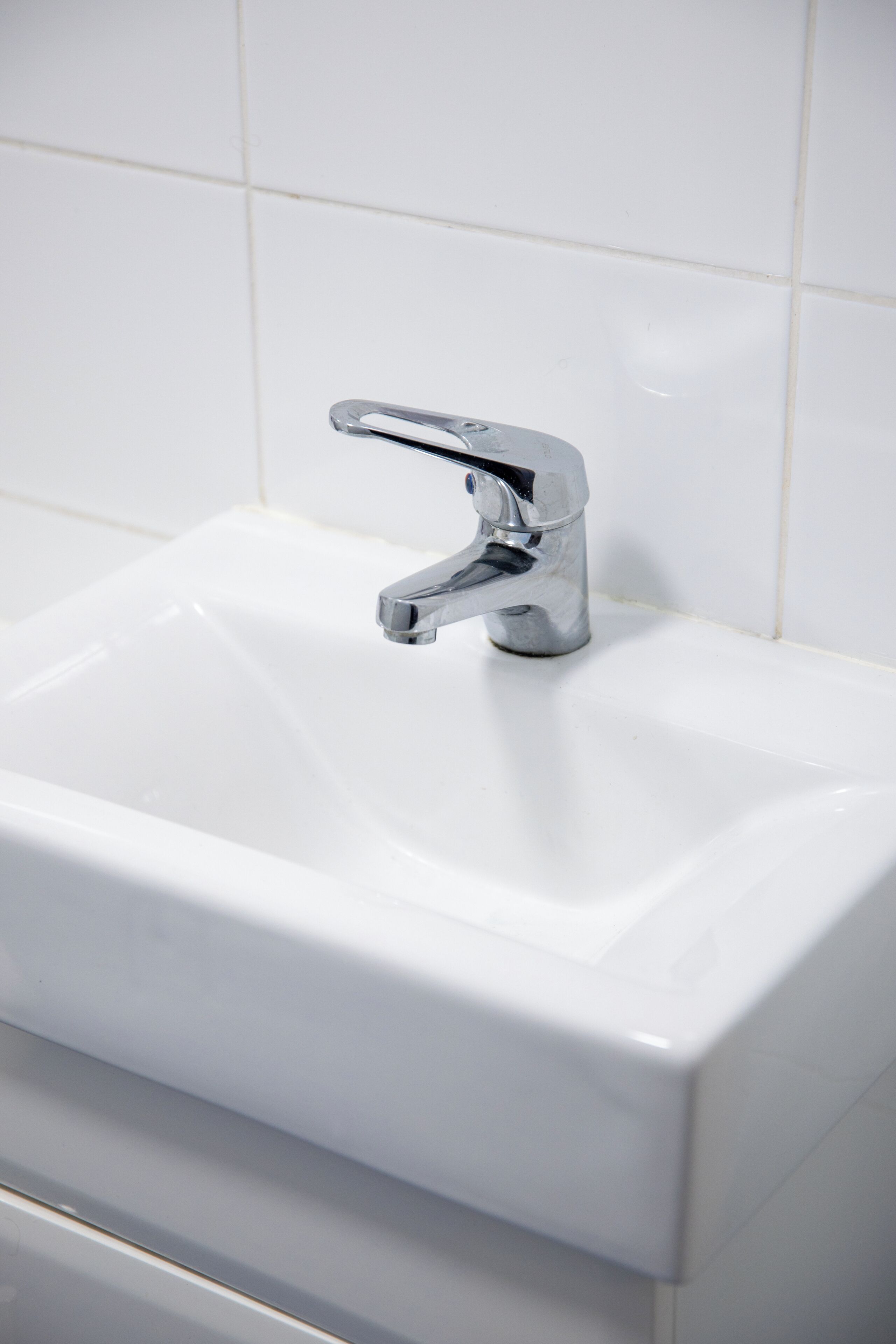 Ein weißes Waschbecken mit chromfarbenem Wasserhahn.