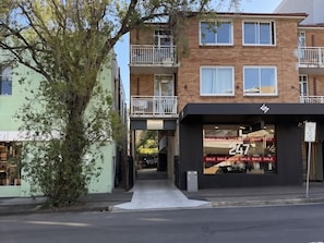 A multi-story building with a ground-level retail space and upper residential units. - Bright Bondi Studio | 2 Min Walk to Beach, Bath, Full Kitchen, Sleeps 4 (Bondi Beach)