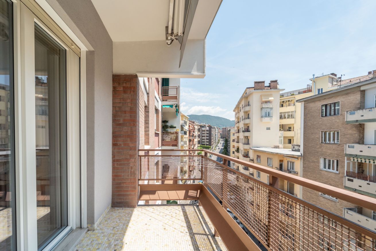 A balcony with a view of neighboring buildings and a mountain in the distance.